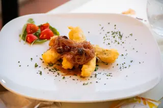 Baccalà fritto con cipolle caramellate, uvetta e pinoli