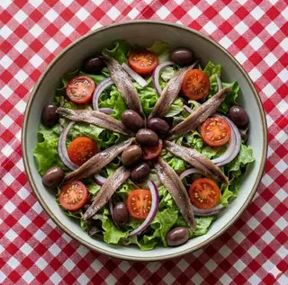 Insalata verde con acciughe, pomodorini, olive liguri e cipolla