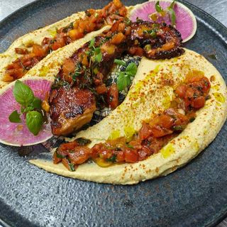 Октопод върху хумус с домати конкасе