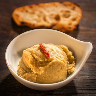 Разядка хумус с печен домат, поднесена с прясно изпечени филийки хляб