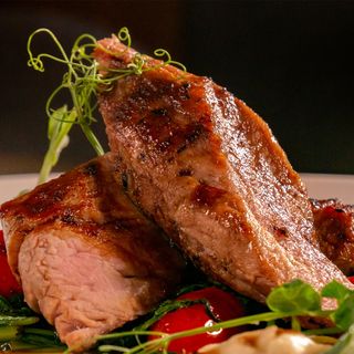 Свинско бон филе от порода Дюрок приготвено на су вид със задушен спанак и чери домати, репички, хрупкава царевица и крем от земна ябълка и трюфел