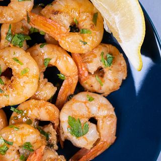 Скариди изпечени в масло, парченца чесън, фламбирани с коняк (200г)