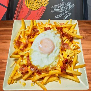 Patatas fritas con beicon, queso y huevo frito