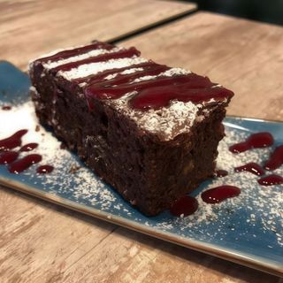Brownie casero de chocolate y almendra tibio con coulis de frambuesa