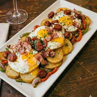 Huevos rotos con patatas, txistorra y bacón