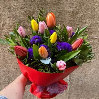 Ramo de tulipanes de color variado con verdes de temporada .