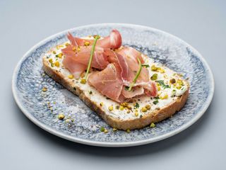 Bruschetta Con jamon serano, queso crema y pistachos picados