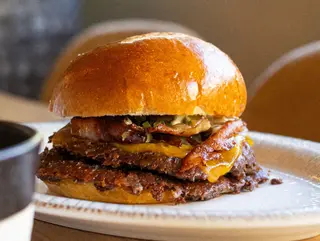 Hamburguesa Smash clásica: doble de carne, beicon crujiente, queso fundido y encurtidos