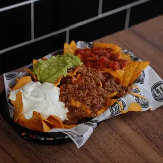 Nachos con cheddar, guacamole, crema agria, pico de gallo y chili con carne