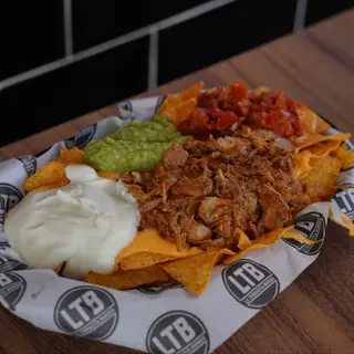 Nachos con cheddar, guacamole, crema agria, pico de gallo y pulled pork con chipotle