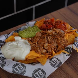 Nachos con cheddar, guacamole, crema agria, pico de gallo y pulled pork con chipotle