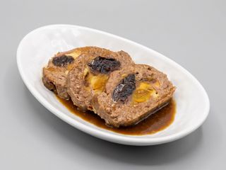 Rollo de carne picada relleno de ciruelas, albaricoque, pasas, jamón y queso en salsa adada