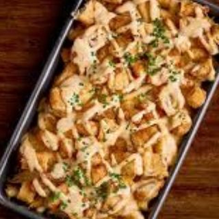 Patatas con salsa Maillard, pollo crispy y cebolla crujiente