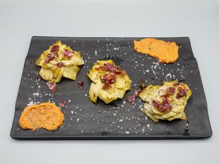Alcachofas confitadas con ibérico y romesco