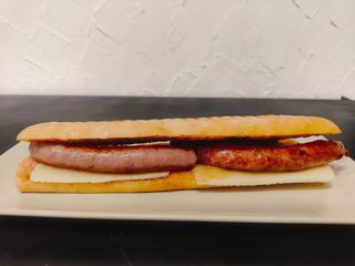 Bocadillo de salchichas, queso y cebolla caramelizada