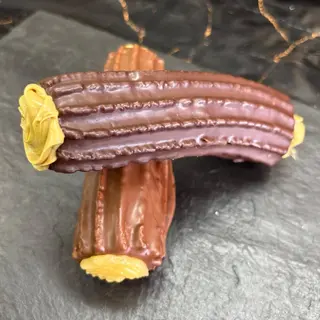 Xuixo cubierto con chocolate relleno de pistacho. 