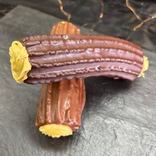 Xuixo cubierto con chocolate relleno de pistacho. 