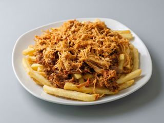 Papas fritas con carne mechada, pollo mechado y salsas.