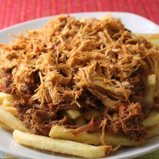 Papas fritas con carne mechada, pollo mechado y salsas.