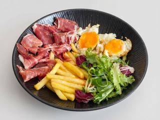 Bol de ensalada con jamón ibérico, huevo y patatas