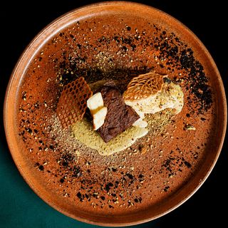 Brownie Sobre Crema De Pistachos Con Tierra Lotus Y Quenelle De Vainilla