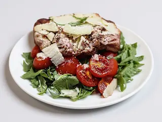 Tagliata con rucola pomodorini e scaglie di pecorino, glassa al cannonau e patate al forno