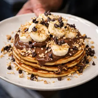 Pancake con Banana, gianduia, granella di nocciole tostate e gocce di cioccolato