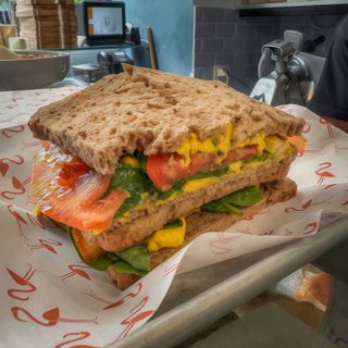 Tramezzino con hummus di ceci, spinaci e pomodoro secco e fresco