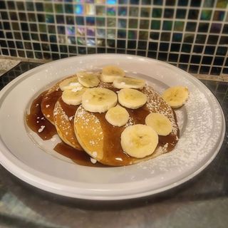 Pancake con sciroppo d'acero, banana fresca e zucchero a velo