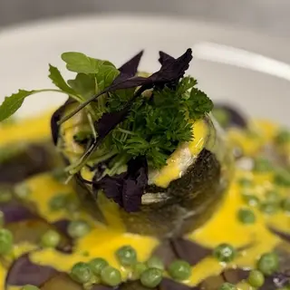 Turbante di spigola su patate viola, salsa allo zafferano e piselli saltati
