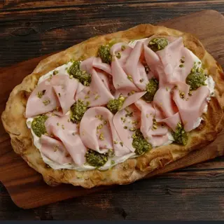 PINSA | LA BOLOGNESE SICULA | Base multicereali, mousse di ricotta, mortadella IGP Bologna, pesto di pistacchio, granella di pistacchio  |