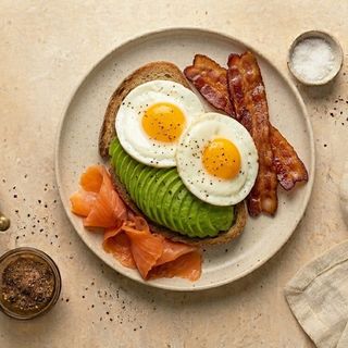 Uova occhio di bue con salmone affumicato, bacon, avocado e pane tostato