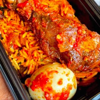 Jollof rice, boiled egg and peppered chicken drumstick