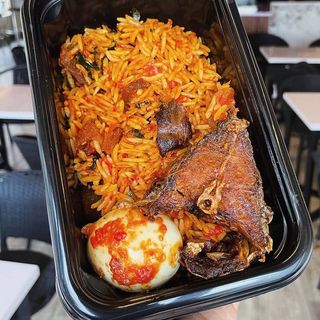 Jollof rice, half tilapia fish and boiled egg in Nigerian spicy sauce 
