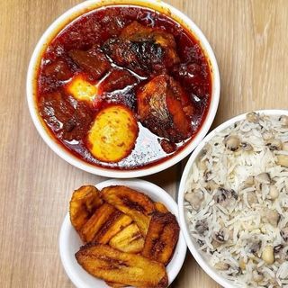 White rice mixed with beans, plantains, 2 boiled eggs mixed with titus fish in spicy stew