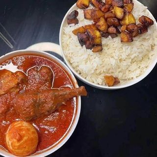 Whiterice and plantains served with titus fish and goatmeat in spicy sauce and boiled egg
