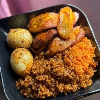 Jollof rice served with plantains and 2 boiled eggs