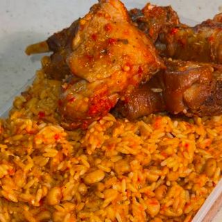 Jollof rice mixed with white oloyin beans served with peppered chicken
