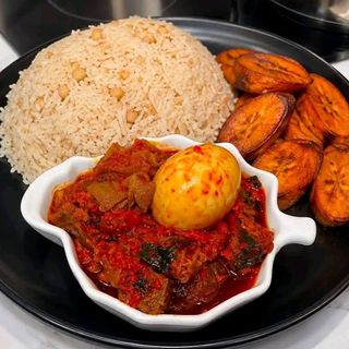 White rice mixed with oloyin beans plantains assorted goatmeat mixed with boiled egg