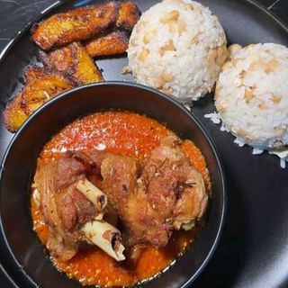White rice mixed with oloyin beans plantains and turkey in spicy Nigerian stew