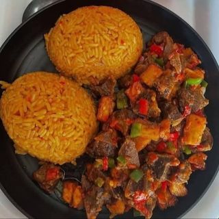 Jollof rice served with spicy Gizzards mixed with carrots, peas and long beans