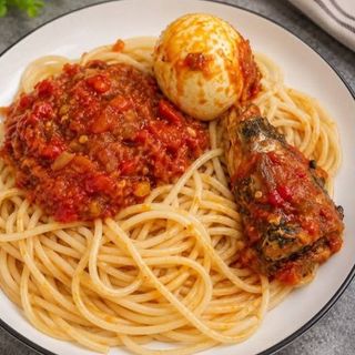Sphaghetti served with boiled egg and peppered titus fish