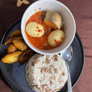 White rice mixed with oloyin beans served with plantains peppered titus fish and 2 boiled eggs