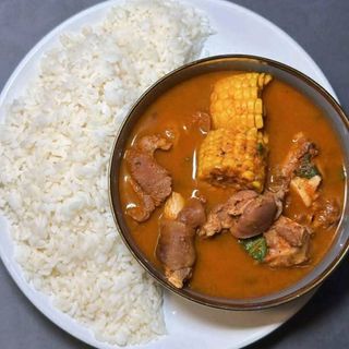 White rice served with goatmeat peppe soup mixed with corn