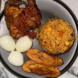 Jollof rice and plantains served with peppered chicken and 3 boiled eggs