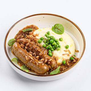 Куриные колбаски с нежным картофельным пюре, под луковым соусом и гарниром из зеленого горошка