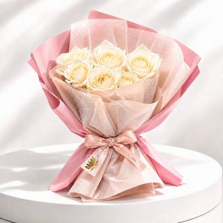 Bouquet de roses blanches emballé dans un papier rose et beige