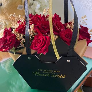 سلة ورود سوداء بورود حمراء جورية مع ورود جافة صغيرة تضيف جمالية للباقة