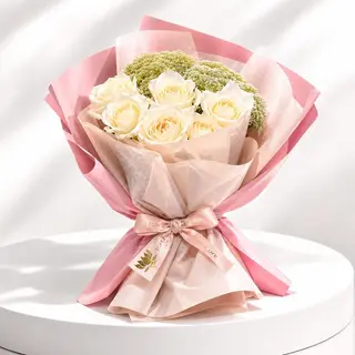 Bouquet de roses blanches emballé dans un papier rose et beige