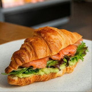 Croissant with salmon, avocado sause , salad, capers